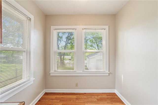 spare room with baseboards and light wood-style floors
