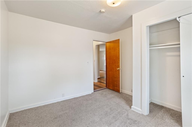 unfurnished bedroom with carpet floors, a closet, and baseboards