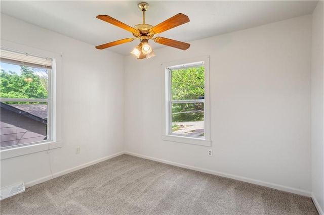 unfurnished room with baseboards, carpet flooring, visible vents, and plenty of natural light