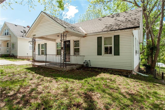 view of front of home with a porch, roof with shingles, and a front yard