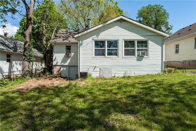 rear view of house with central air condition unit, fence, cooling unit, and a lawn