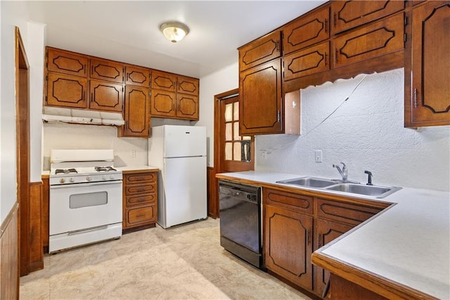kitchen with a sink, brown cabinetry, white appliances, under cabinet range hood, and light countertops
