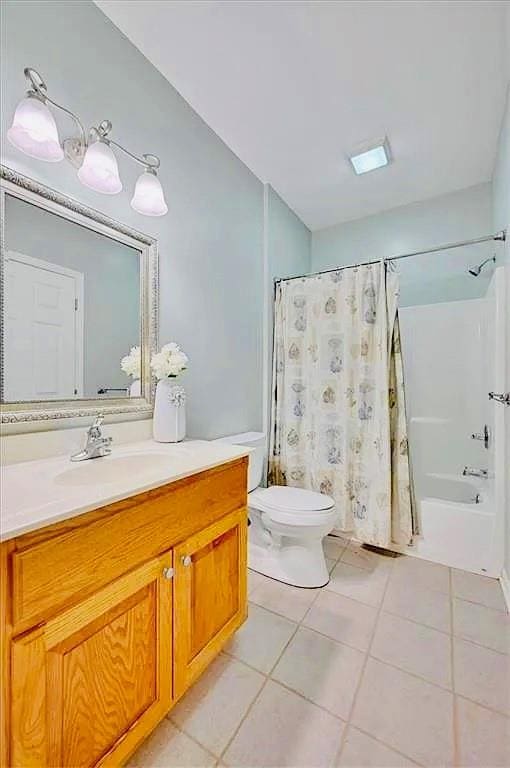 full bathroom featuring toilet, tile patterned floors, shower / bath combination with curtain, and vanity