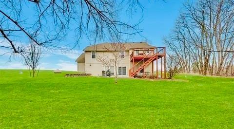 rear view of house with stairway, a yard, and a wooden deck