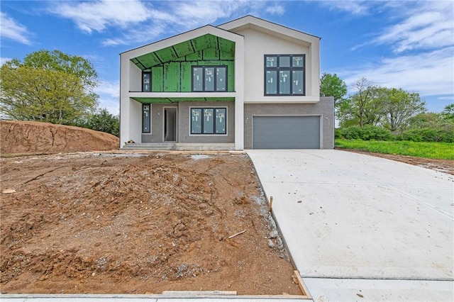 contemporary home featuring concrete driveway, an attached garage, and stucco siding