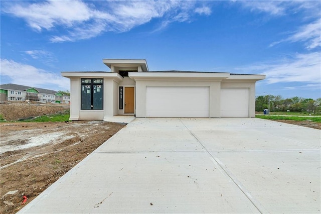 prairie-style home featuring stucco siding, concrete driveway, and an attached garage