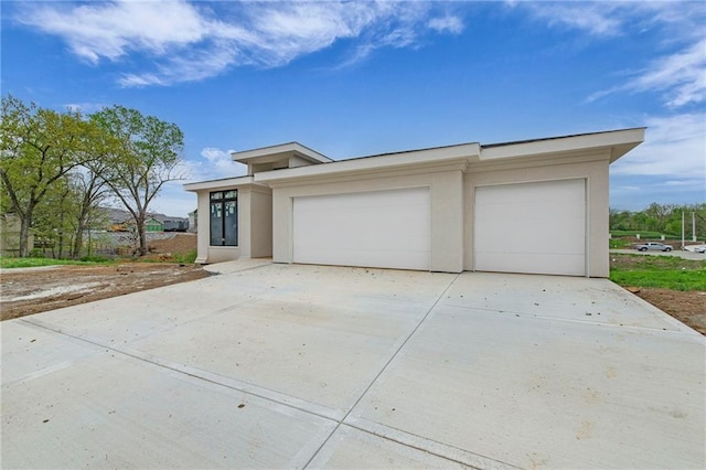 view of front of house with stucco siding, driveway, and an attached garage