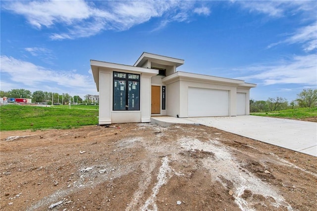 prairie-style house with stucco siding, driveway, and a garage