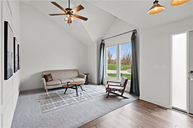 living area with baseboards, wood finished floors, vaulted ceiling, and a ceiling fan
