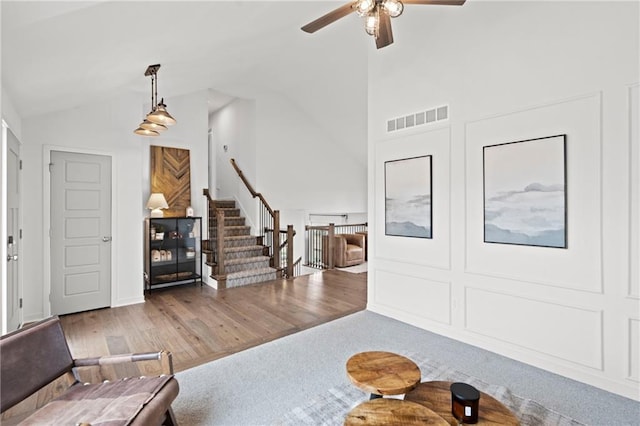 living room with a ceiling fan, wood finished floors, lofted ceiling, and visible vents
