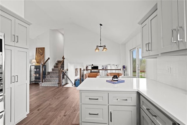 kitchen featuring light countertops, a chandelier, a peninsula, wood finished floors, and gray cabinetry
