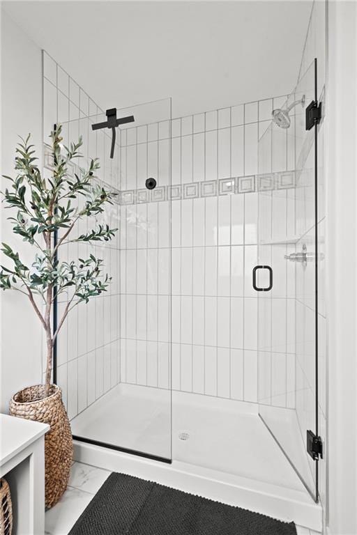 bathroom with marble finish floor and a stall shower