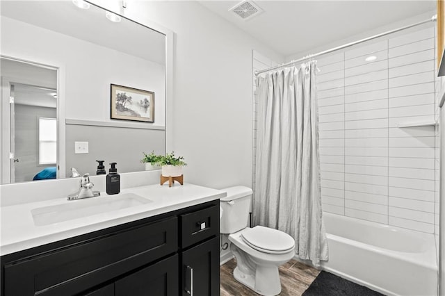 full bathroom with vanity, shower / tub combo with curtain, toilet, visible vents, and wood finished floors