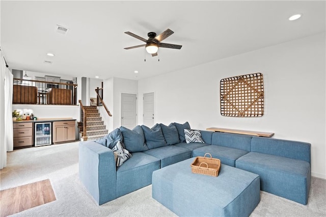 living area with wine cooler, a dry bar, visible vents, a ceiling fan, and light carpet