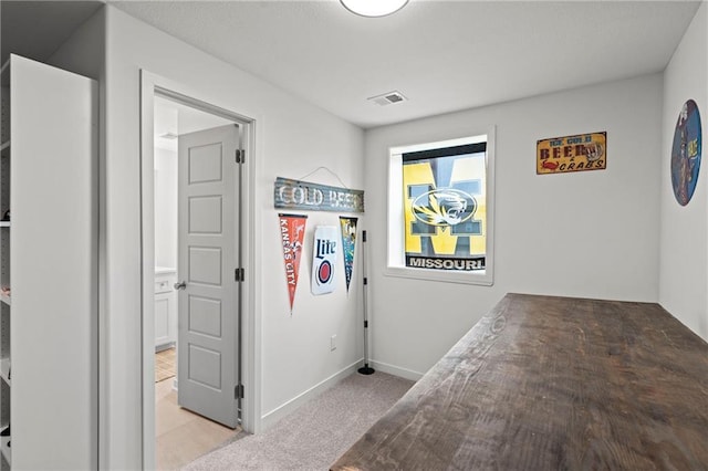 corridor featuring baseboards, light colored carpet, and visible vents
