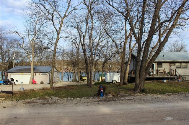 view of front of property featuring driveway, a wooden deck, and an outbuilding