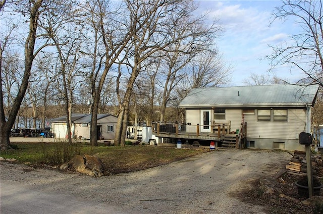 view of front of property with metal roof, a deck, and dirt driveway