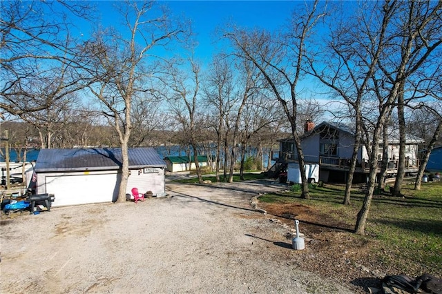 view of front of home with metal roof, a garage, a chimney, dirt driveway, and stairway
