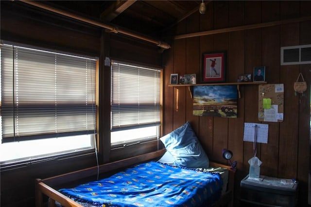 bedroom featuring wood walls, visible vents, and vaulted ceiling