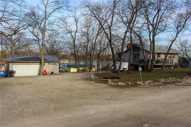 exterior space with driveway, an outdoor structure, a wooden deck, and a garage