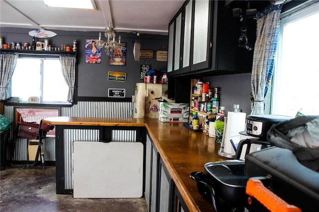 kitchen with dark cabinetry, concrete floors, and a chandelier