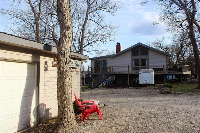 view of side of home with a deck, a garage, and a chimney