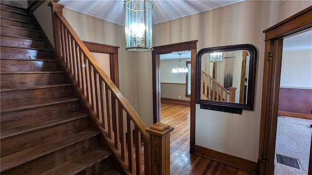 2023 Linden Rd, Hiawatha, KS 66434 - stairs with visible vents, wood finished floors, baseboards, and an inviting chandelier