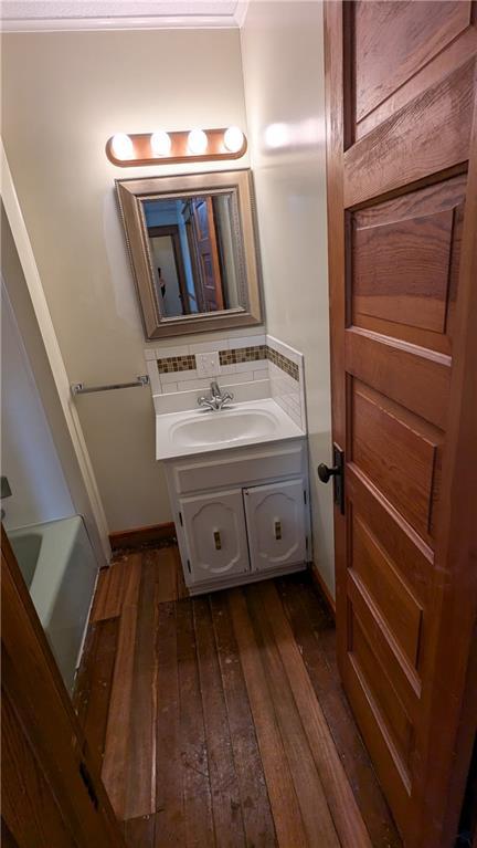 2023 Linden Rd, Hiawatha, KS 66434 - bathroom featuring vanity, a washtub, hardwood / wood-style flooring, and decorative backsplash