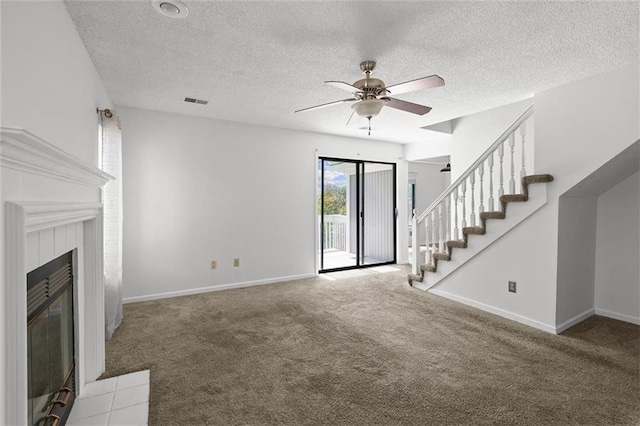 unfurnished living room featuring carpet floors, ceiling fan, a textured ceiling, stairs, and baseboards