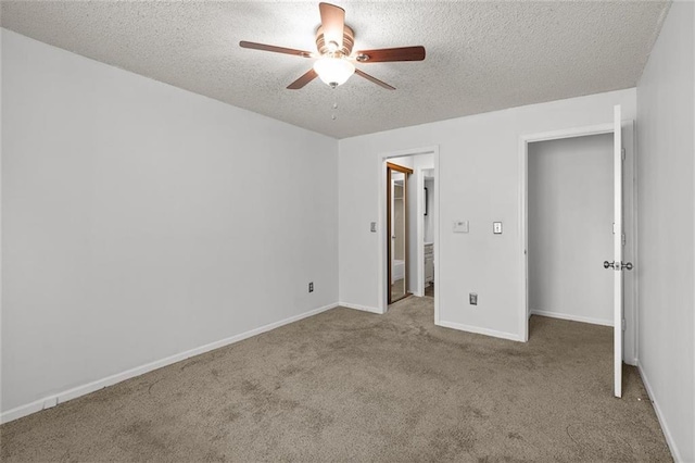 unfurnished bedroom with a textured ceiling, carpet floors, baseboards, and a ceiling fan
