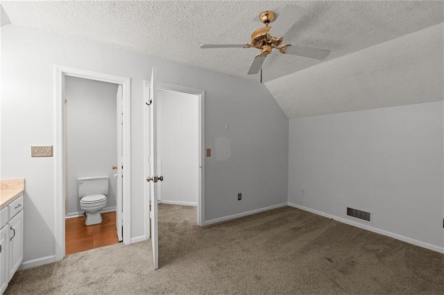 additional living space featuring light colored carpet, a ceiling fan, a textured ceiling, lofted ceiling, and baseboards