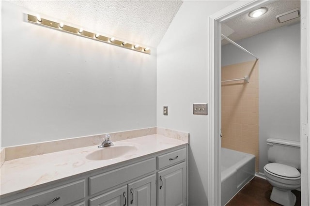 bathroom featuring a textured ceiling, vanity, toilet, and tub / shower combination