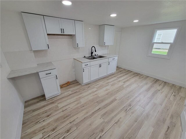 6211 Washington St, Saint Joseph, MO 64504 - kitchen featuring decorative backsplash, white cabinetry, a sink, and light wood finished floors