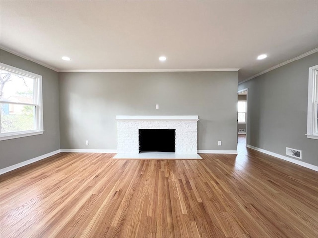 unfurnished living room with light wood finished floors, baseboards, visible vents, and a wealth of natural light