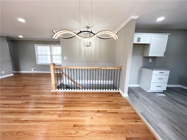 unfurnished dining area with baseboards, recessed lighting, crown molding, and light wood finished floors