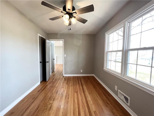 unfurnished bedroom featuring baseboards, visible vents, a ceiling fan, and wood finished floors