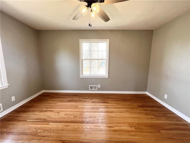 spare room with baseboards, ceiling fan, visible vents, and wood finished floors