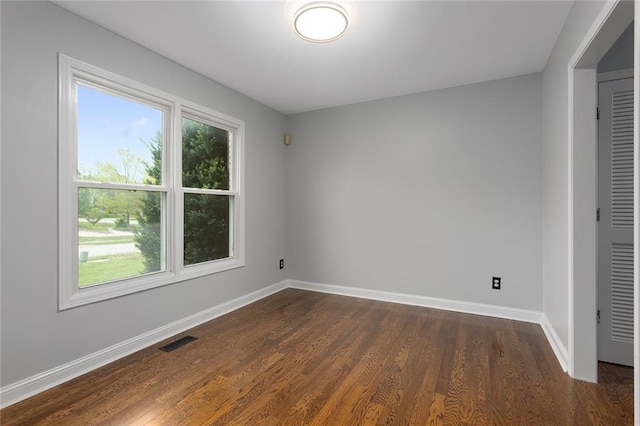 empty room with visible vents, baseboards, and dark wood-style flooring
