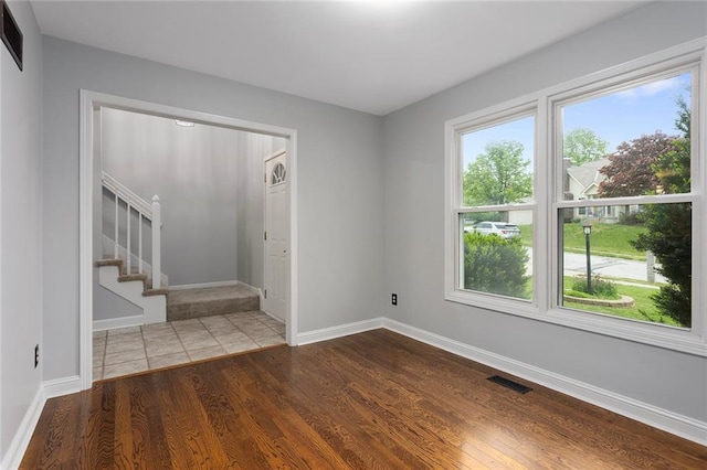empty room featuring visible vents, baseboards, wood finished floors, and stairway