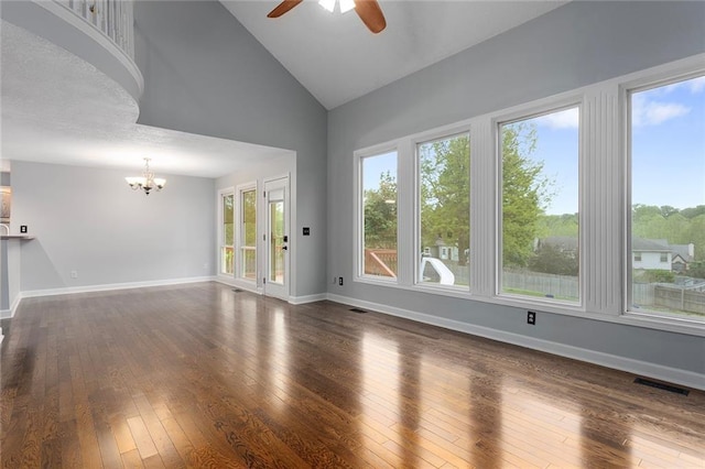 unfurnished living room with visible vents, baseboards, high vaulted ceiling, dark wood finished floors, and ceiling fan with notable chandelier