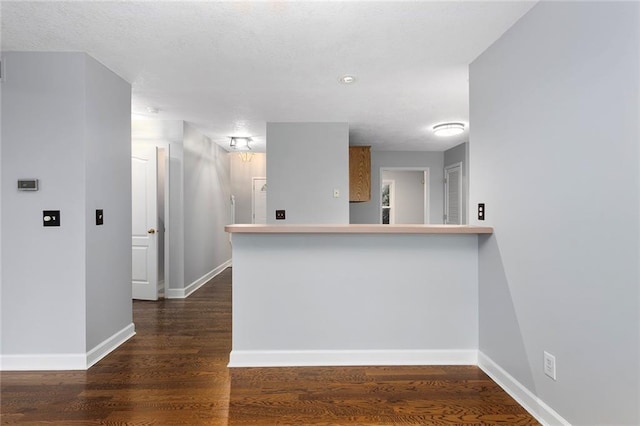 kitchen featuring a peninsula, baseboards, and wood finished floors