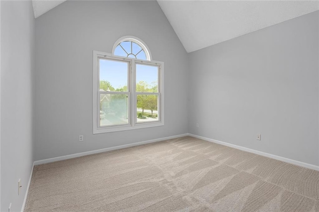 carpeted empty room featuring baseboards and vaulted ceiling