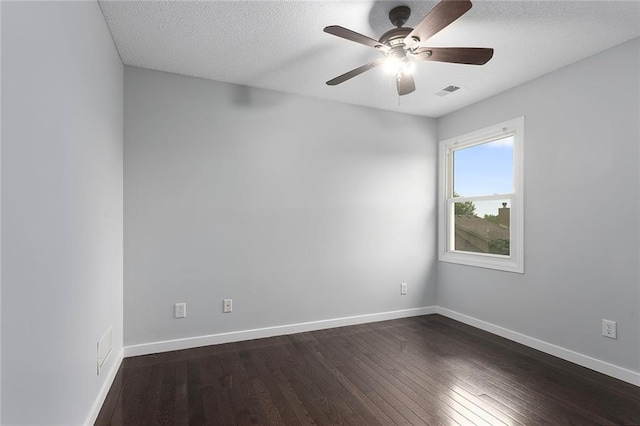 unfurnished room with visible vents, a ceiling fan, dark wood-style flooring, and baseboards