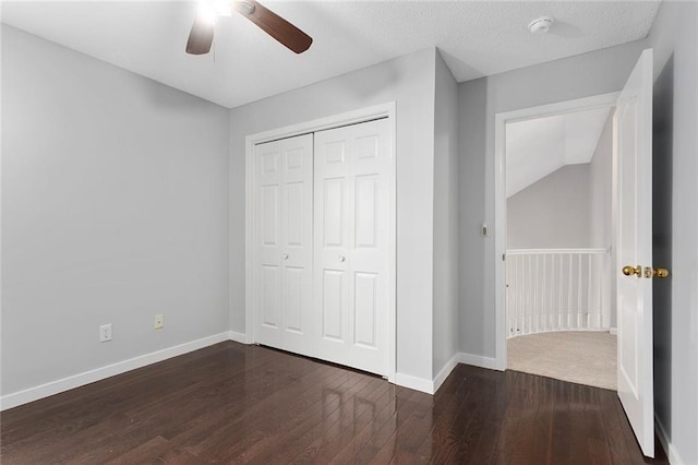 unfurnished bedroom with a closet, dark wood-style flooring, ceiling fan, and baseboards
