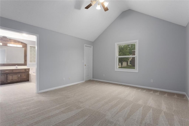 unfurnished bedroom featuring baseboards, ensuite bathroom, vaulted ceiling, and light carpet