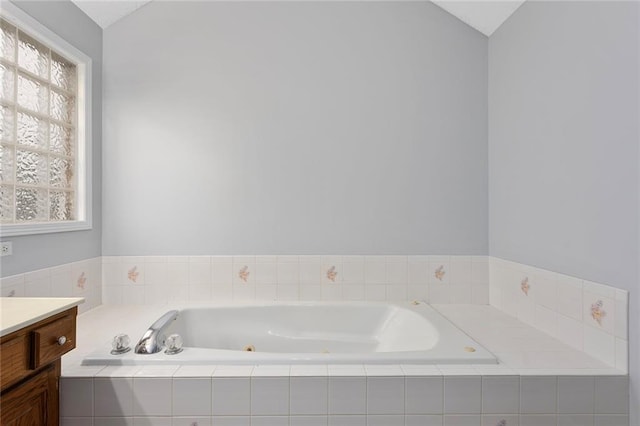 full bath featuring a whirlpool tub, lofted ceiling, and vanity