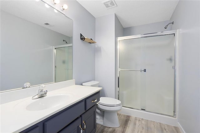 full bath featuring visible vents, a shower stall, wood finished floors, vanity, and toilet