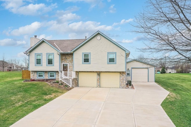 split foyer home with an attached garage, a chimney, stone siding, and a front lawn