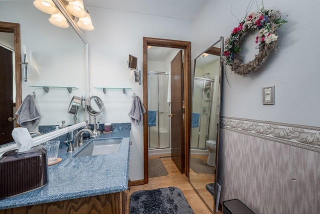full bath with toilet, a stall shower, wood finished floors, and vanity