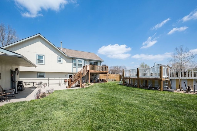 back of property featuring a patio area, stairs, a wooden deck, fence, and a lawn